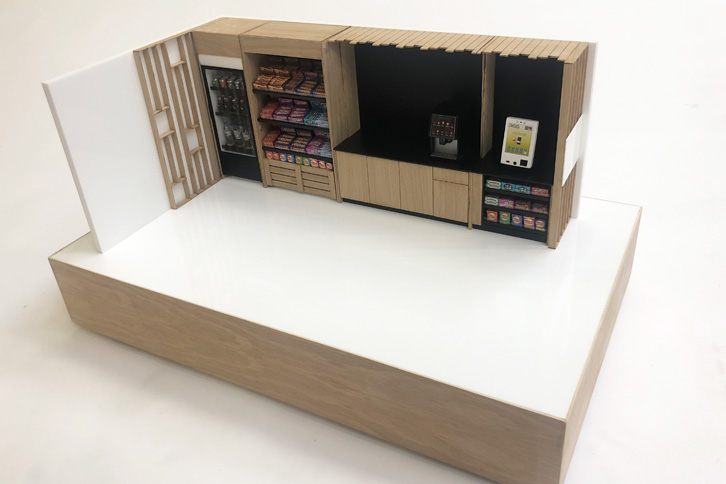 1:12 scale model of a micromarket. The model is made from laser cut gloss white acrylic and oak. It is animated with scale model food and till ans ditting on a veneered baseboard.