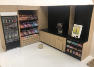 1:12 scale model of a micromarket. The model is made from laser cut gloss white acrylic and oak. It is animated with scale model food.