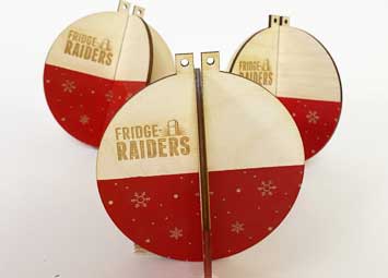 Laser cut slot together Christmas baubles made from laser cut plywood. They are painted red and laser engraved with Fridge Raiders logo. .