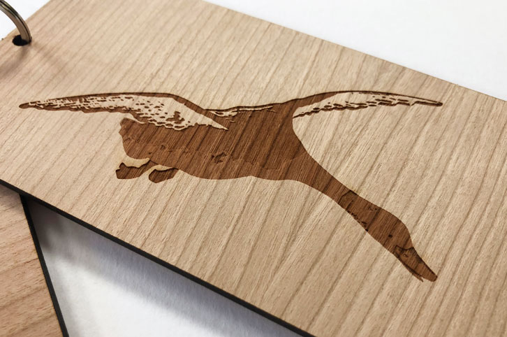 Close up of laser engraved duck on a hotel room key fob. Laser cut and etched from cherry wood laminated timber.