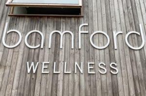 Large white, cnc machined, sign letters mounted on a wood clad wall for Bamford Wellness Spa.