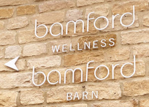 Laser cut white letters on a Cotswold stone wall at Bamfords Spa,