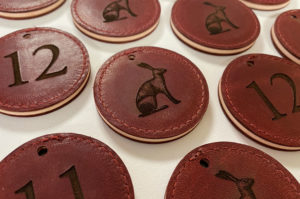 Laser engraved red leather keyfobs with an image of a hare and room numbers.