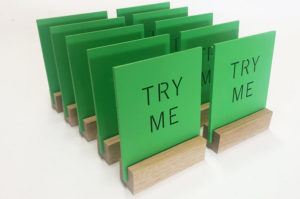 Bespoke laser cut plywood shop signs. Painted pantone matched green with a solid oak slotted base.